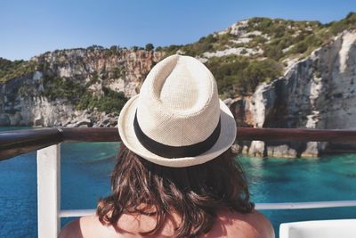 Rear view of woman at sailing in boat by mountain against clear sky