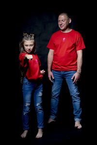 Portrait of teenage girl standing against black background