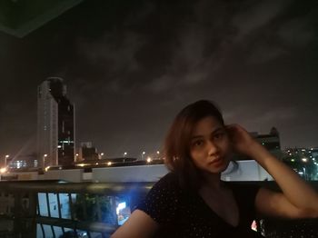 Portrait of young woman holding illuminated against sky at night