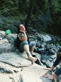 Happy woman siting on rock in forest 