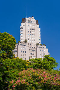 Low angle view of trees against clear blue sky