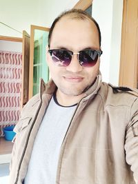 Portrait of young man wearing sunglasses at home