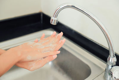 Cropped image of woman hand with faucet at home