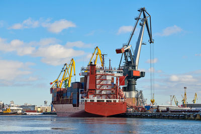 Moored cargo ship and harbor cranes in port. cargo container yard, container ship terminal, shipyard