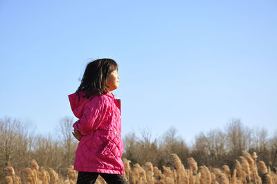 Girl standing on field against clear sky