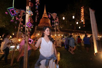Group of people standing against illuminated lights at night