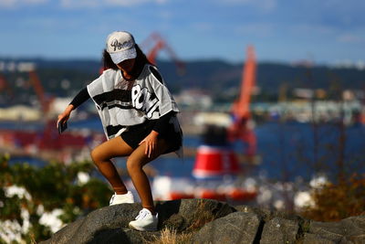 Woman sitting on rock against sky