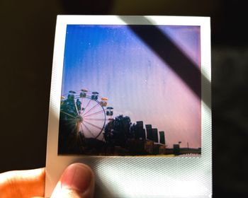 Close-up of person holding umbrella against blue sky