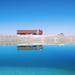 Lifeguard hut by sea against clear blue sky