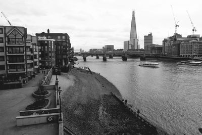 View of buildings by river against sky in city