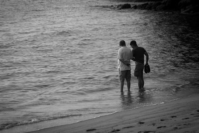 Rear view of friends standing on beach