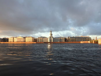 Sea by buildings against sky in city