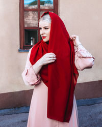 Mid adult woman standing against red wall