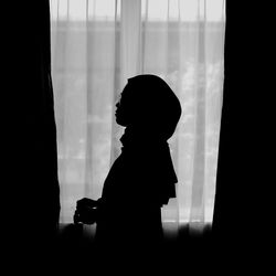 Silhouette man standing by window at home