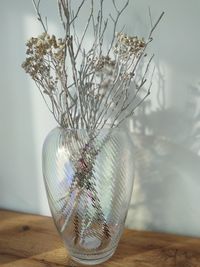 Close-up of vase and dried flowers on table in the sunshine