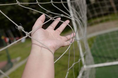 Close-up of hand holding goal post net