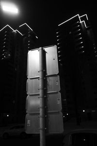 Low angle view of illuminated street by building at night