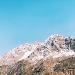 Low angle view of snowcapped mountain against clear blue sky