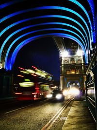 Illuminated light trails on road in city against sky at night