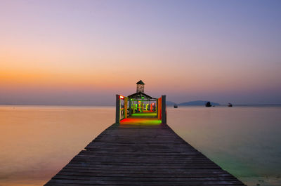 Pier over sea against clear sky during sunset