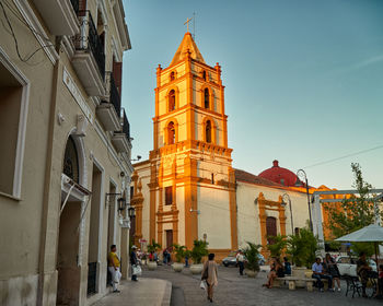 People walking on street amidst buildings in city against sky