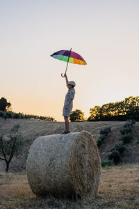 Rear view of woman with umbrella on field against clear sky