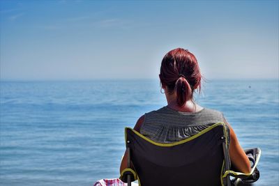 Rear view of woman standing by sea against clear sky