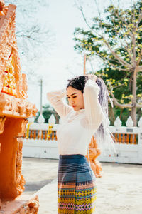 Young woman looking away while standing outdoors