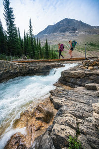 Crossing raging glacial river on suspension bridge over twin falls