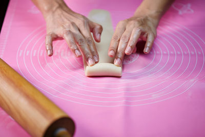 Woman's hands molding the rolle shape dough on pink silicone mesh