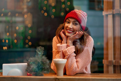 Portrait of young woman wearing knit hat sitting at restaurant
