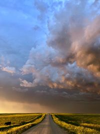 Road amidst field against sky