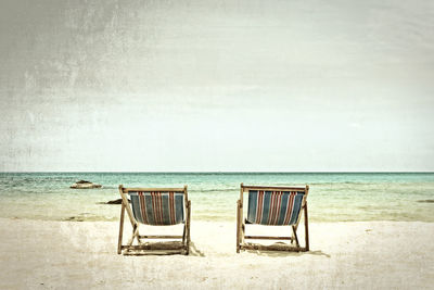 Chair on beach against sky