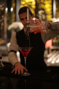 Bartender pouring drink at bar counter