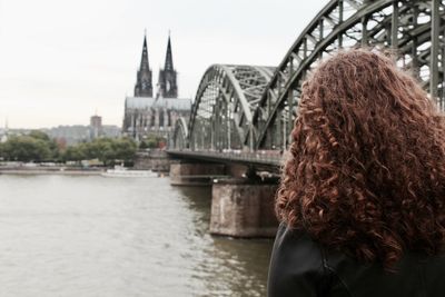 Rear view of woman standing by rhine river against cologne cathedral in city