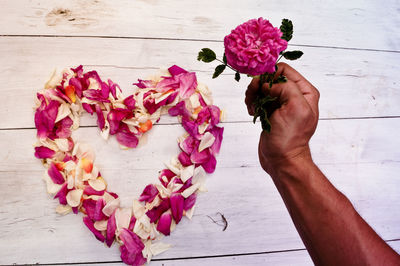 Cropped hand holding flower by heart shaped floral decoration