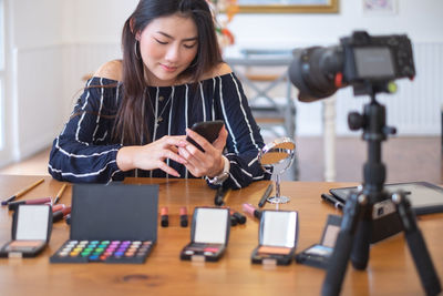 Young woman using phone while sitting on table