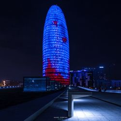 Illuminated buildings against blue sky at night