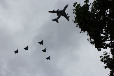 Low angle view of silhouette airplane flying against sky