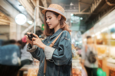 Young woman photographing while standing outdoors