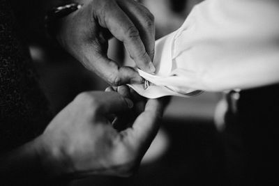 Cropped hands of man buttoning friend cuffs