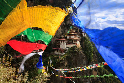 Multi colored flags hanging on mountain against blue sky