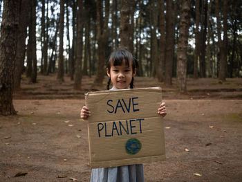 Portrait of happy girl standing by tree in forest