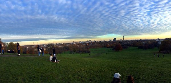 People on field against sky during sunset