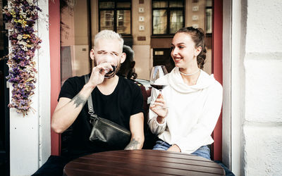 Young couple holding wineglass while sitting at cafe