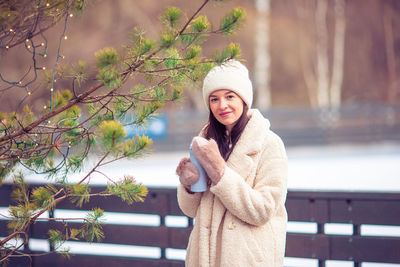 Portrait of young woman standing against trees