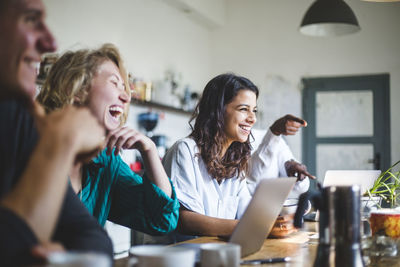 Confident cheerful it professionals sitting at table while working in creative office