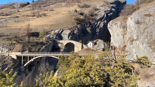 Arch bridge on rock against sky