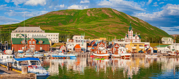 Scenic view of river by buildings in city against sky