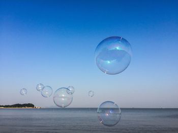 Bubbles over sea against blue sky